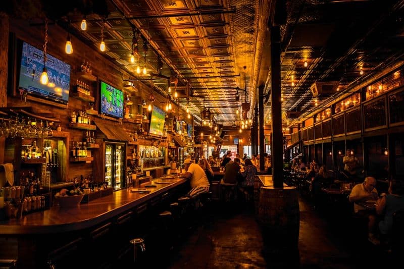 Barra de madera de un bar con clientes al fondo